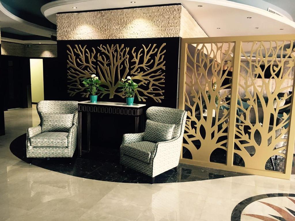 two chairs and a table in a lobby with a wall at Royal View Hotel in Ras al Khaimah