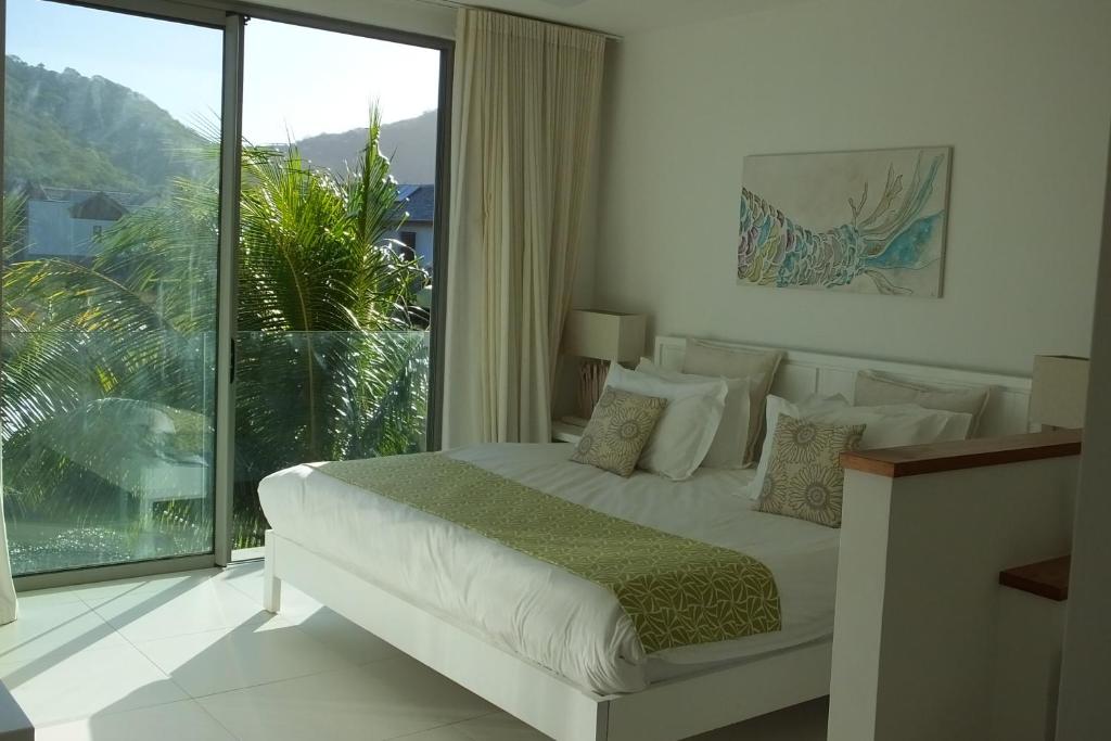 a bedroom with a bed and a large window at 2 bedrooms charming apartment, West Island Resort in Rivière Noire