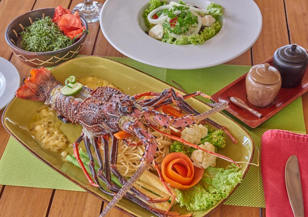 a lobster on a plate of food on a table at Cocotinos Sekotong Lombok in Sekotong
