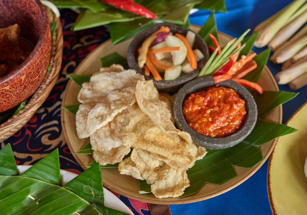 a plate of food with dip and chips and vegetables at Cocotinos Sekotong Lombok in Sekotong