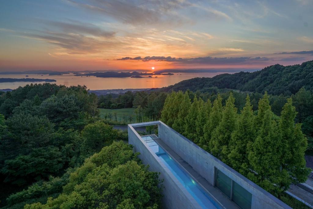 松山市にあるSETOUCHI RETREAT by Onko Chishinのスイミングプール付きの家から夕日を望めます。