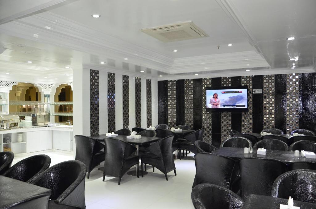 a dining room with black chairs and tables and a television at White Fort Hotel in Dubai