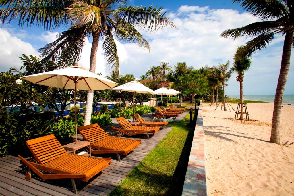 a row of chairs and umbrellas on the beach at Kuiburi Hotel & Resort in Kui Buri