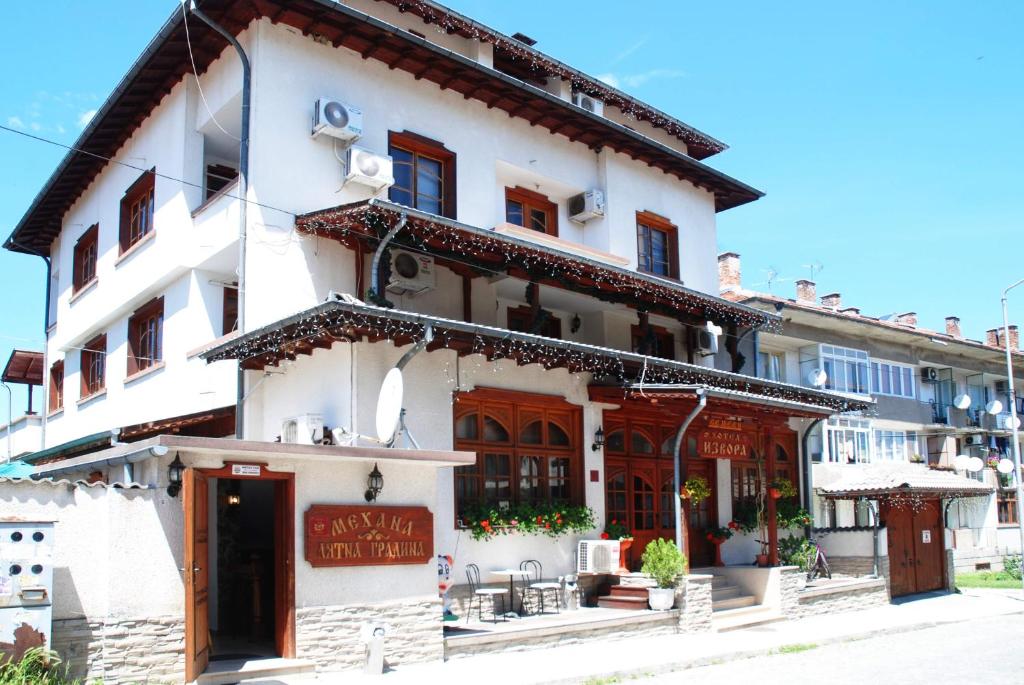 a white building with a sign in front of it at Family Hotel Izvora in Tryavna