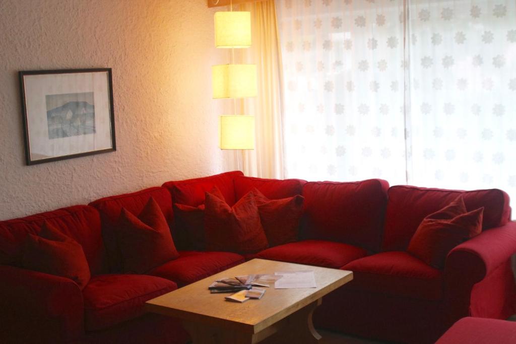 um sofá vermelho numa sala de estar com uma mesa de centro em FeWo Heitmann em Oberjoch