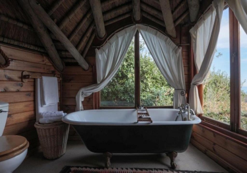 eine große Badewanne in einem Raum mit Fenstern in der Unterkunft Monkey Valley Resort in Noordhoek