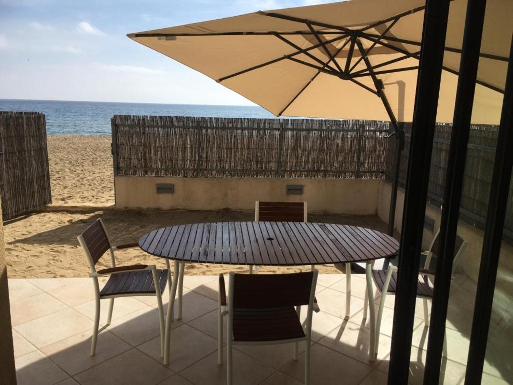 a table and chairs with an umbrella on the beach at Appartement face à la mer in La Croix-Valmer