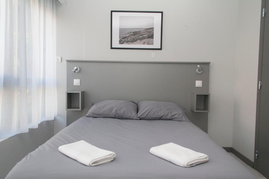 una camera da letto con un letto e due asciugamani di Smartappart Caen Grusse a Caen