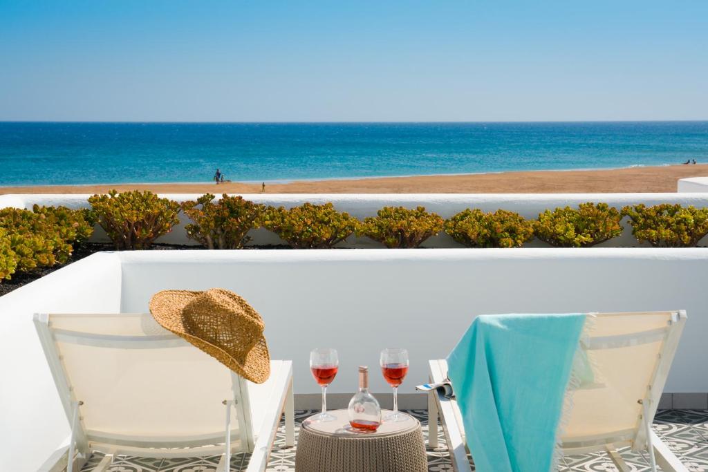 La Concha Boutique Apartments - Adults Only في أريثيفي: طاولة مع كأسين من النبيذ على شرفة مع المحيط