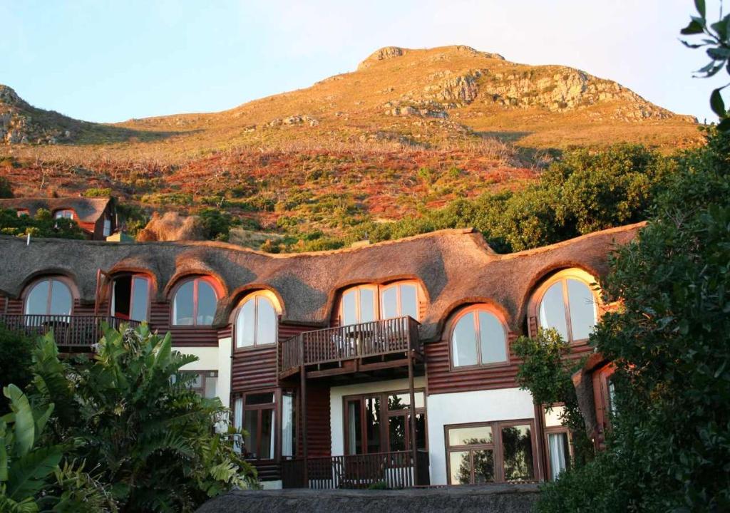 a building with a roof with a mountain in the background at Monkey Valley Resort in Noordhoek