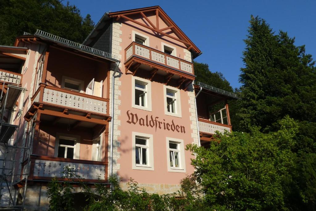 バート・シャンダウにあるBio-Hotel Villa Waldfriedenの看板が貼られたピンクの建物
