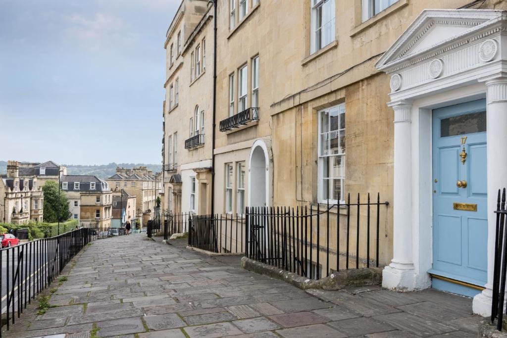a cobblestone street in front of buildings with blue doors at Ainslie's Apartment Belvedere in Bath