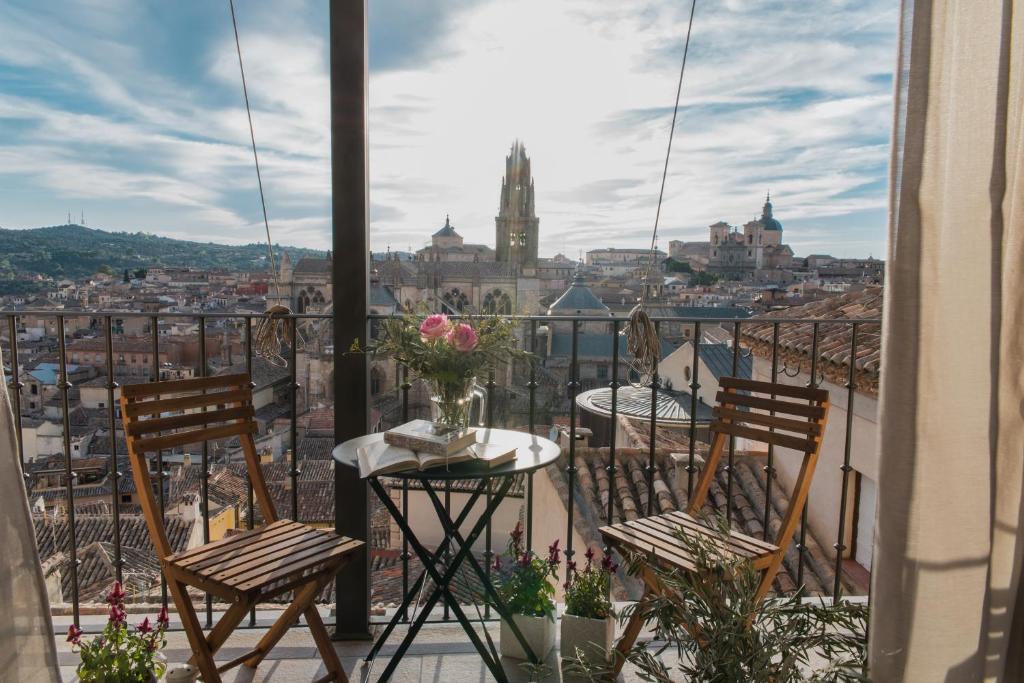 un balcón con 2 sillas y una mesa con flores en El Horno de los Bizcochos en Toledo