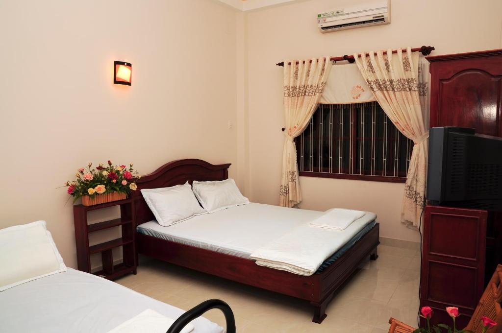 1 Schlafzimmer mit 2 Betten, einem TV und einem Fenster in der Unterkunft Diep Anh Guest House in Ho-Chi-Minh-Stadt