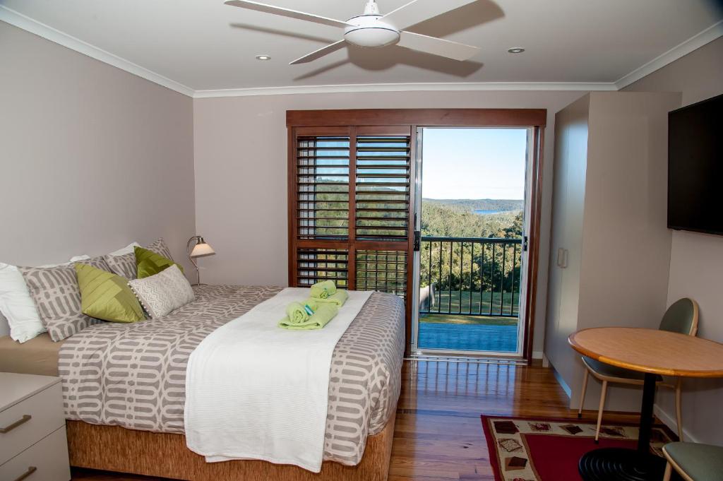 a bedroom with a bed and a table and a window at Sinclairs Country Retreat in Conjola