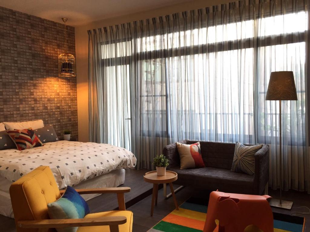 a bedroom with a bed and a couch next to a window at Ho.Me-Easyhouse in Tainan