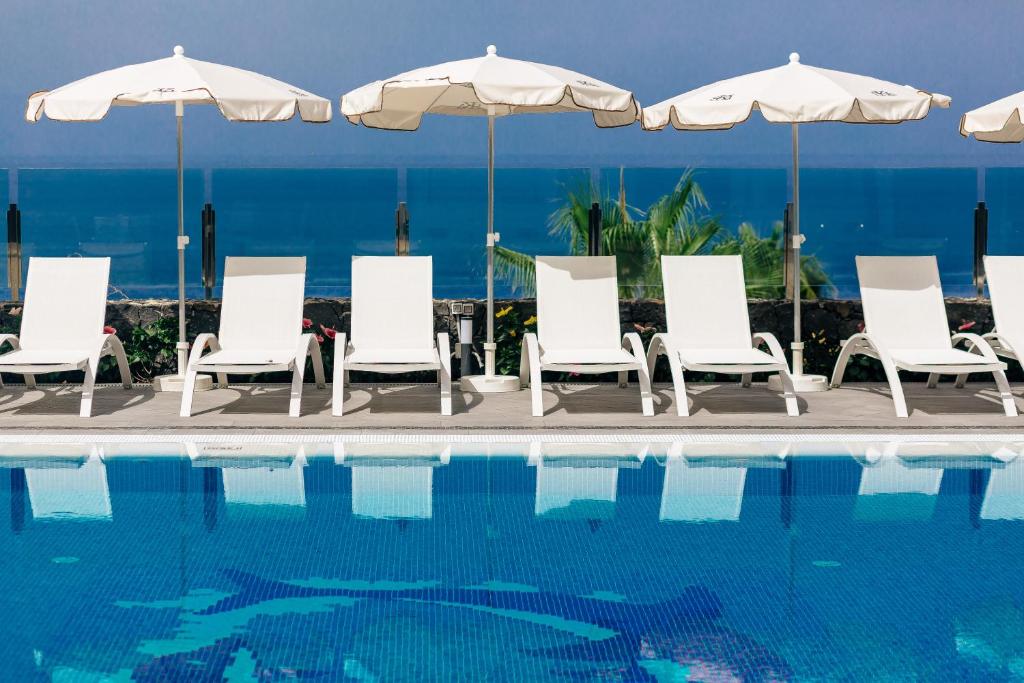 - un groupe de chaises longues et de parasols à côté de la piscine dans l'établissement Klayman Diamond Aparthotel, à Acantilado de los Gigantes