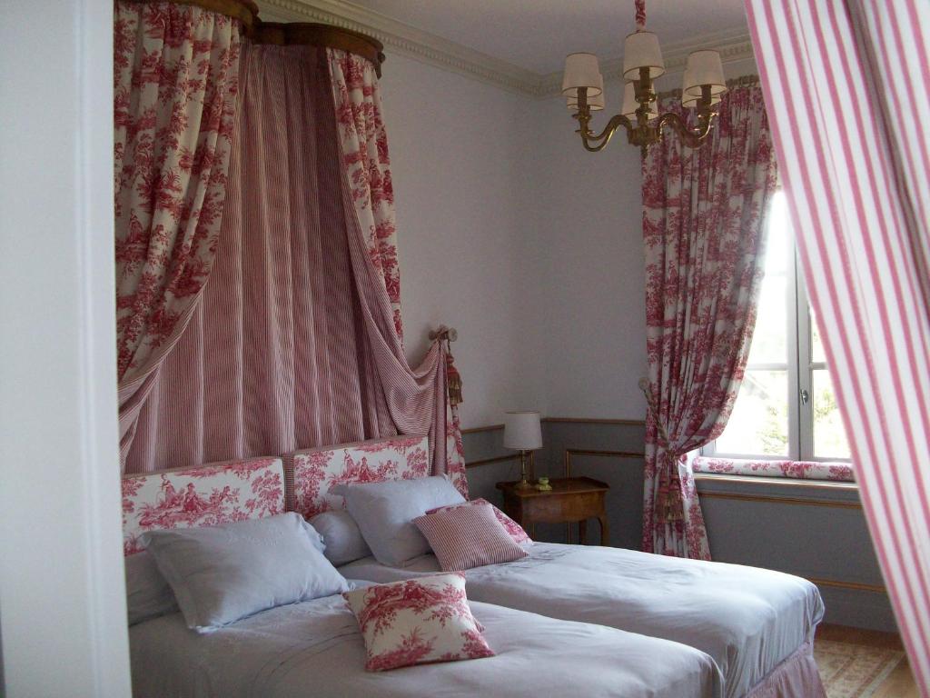 um quarto com uma cama com cortinas vermelhas e brancas em La Thebaide em Saint-Trivier-de-Courtes