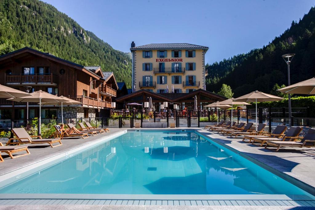 Excelsior Chamonix Hôtel & Spa في شامونيه مون بلان: فندق فيه مسبح وبه كراسي ومبنى