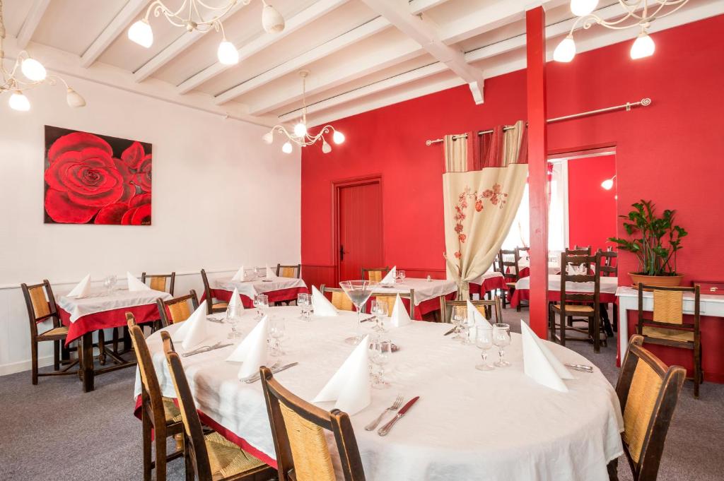 Logis Hotel Restaurant Le Cygne في Yssingeaux: غرفة طعام بمناضد بيضاء وكراسي وجدران حمراء