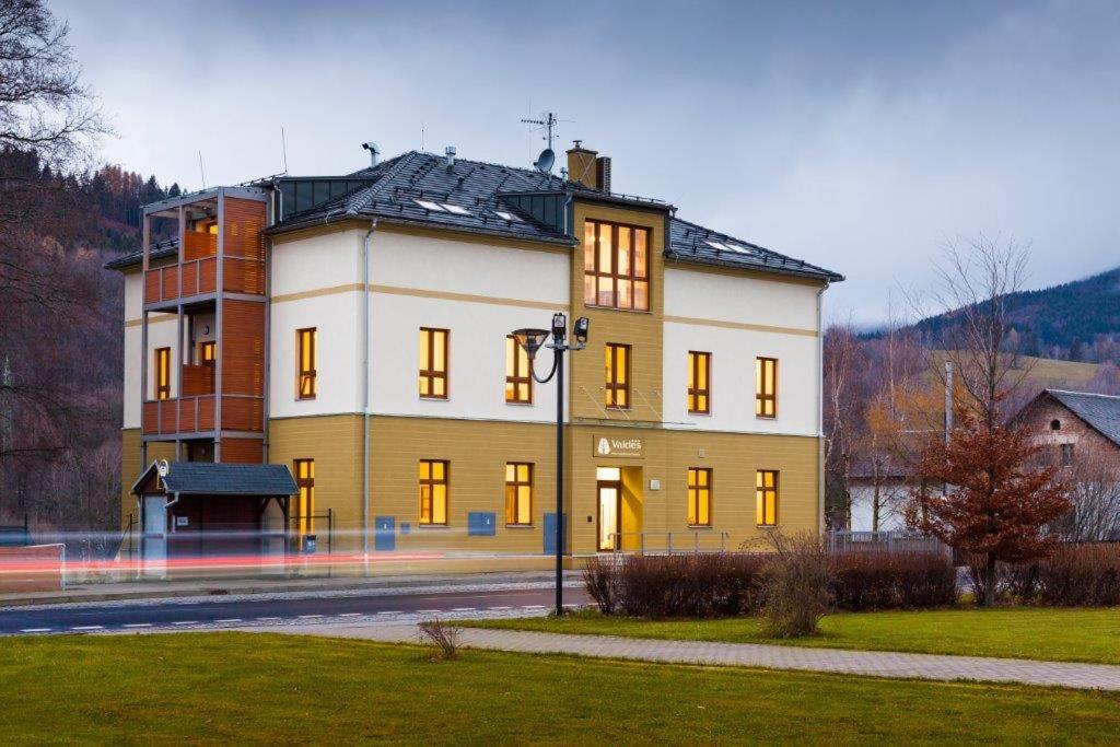 a large yellow and white building on the side of a street at Hotel Valdes in Loučná nad Desnou