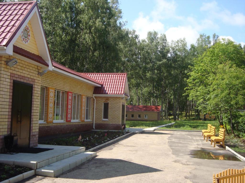 a yellow house with a red roof and benches at Yasnaya Polyana in Arzamas