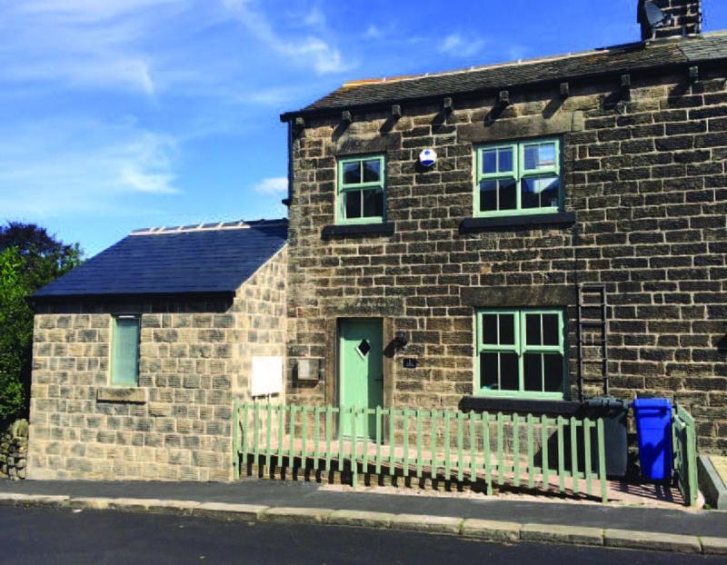 a brick house with a green door on a street at Plough Cottage in Bradfield