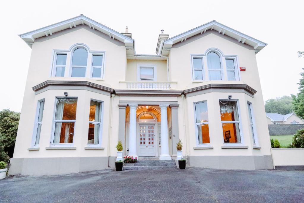 una casa blanca con muchas ventanas en Knockeven House, en Cobh