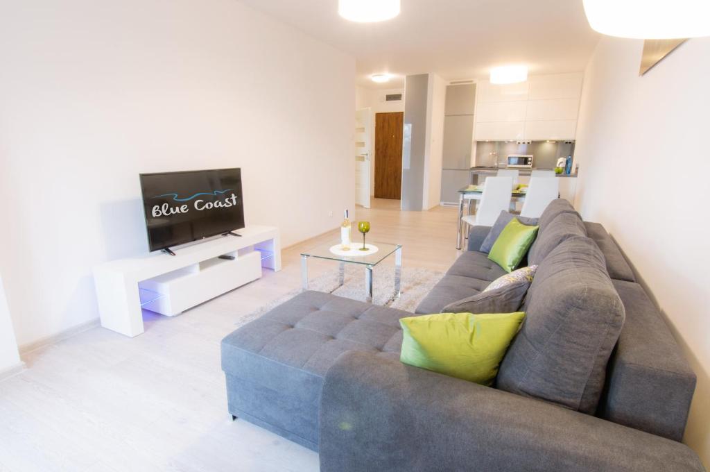 ein Wohnzimmer mit einem Sofa und einem TV in der Unterkunft Apartament z Garażem Solna 11C/306 in Kołobrzeg