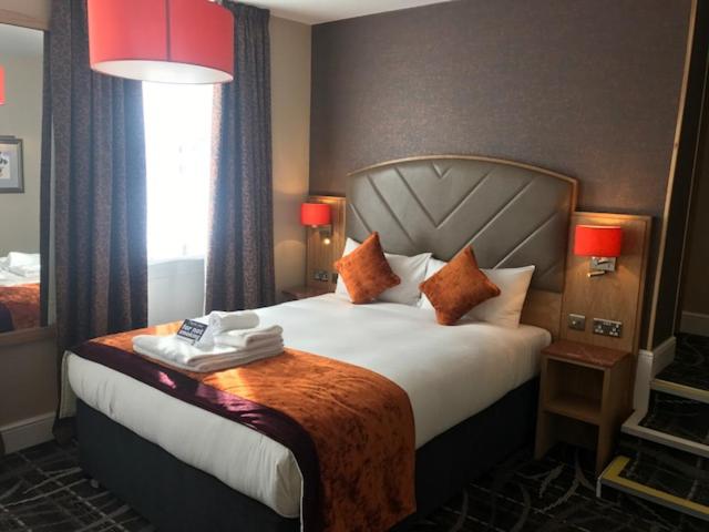 a hotel room with a large bed and a window at The Crown Hotel Wetherspoon in Biggleswade