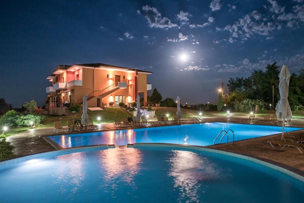 a swimming pool in front of a house at night at Petrinos Lofos in Mándra
