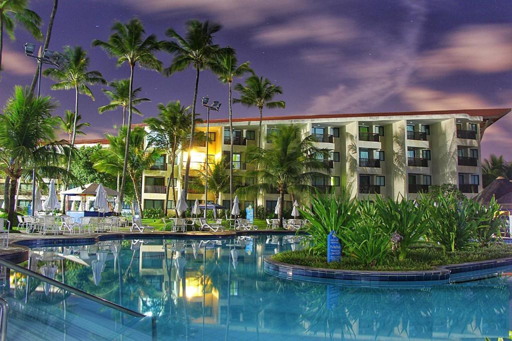 a hotel with a swimming pool in front of a building at Flats Marulhos Resort by BMS in Porto De Galinhas