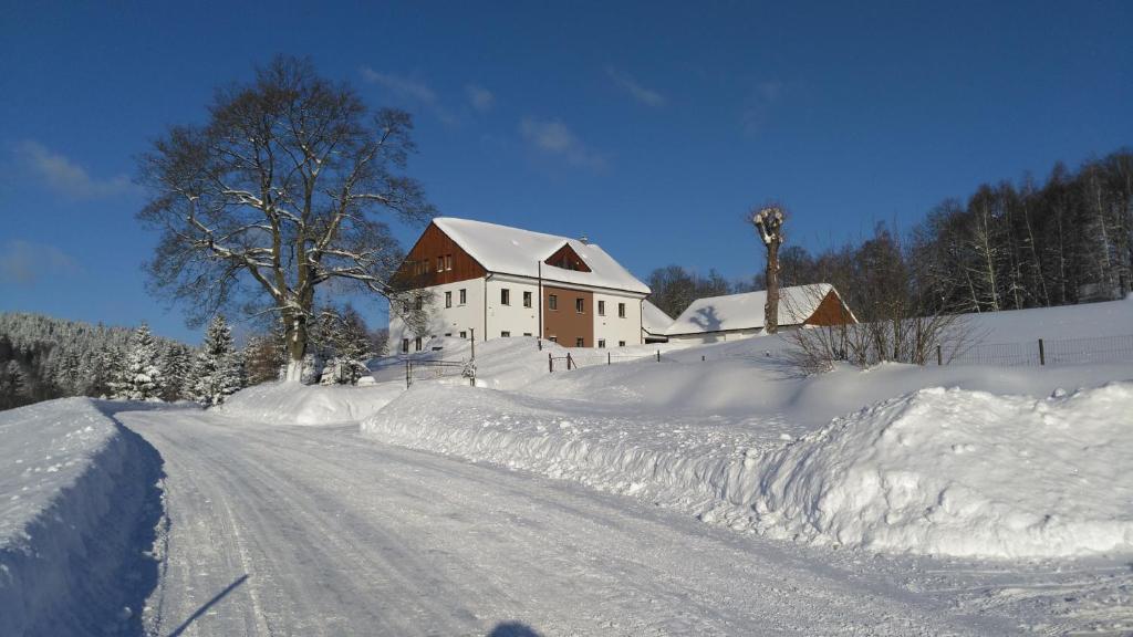 a snow covered road with a house in the background at APARTMÁNY NA VÝSLUNÍ in Horní Maxov