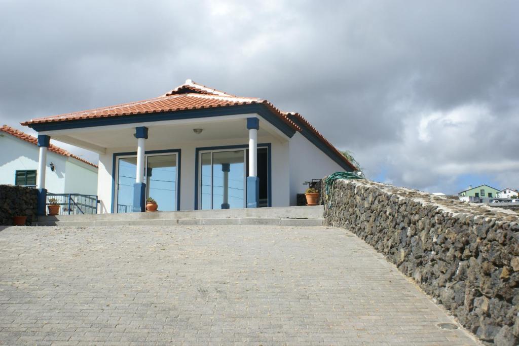 a small white house with a stone wall at Water front view in Angra do Heroísmo