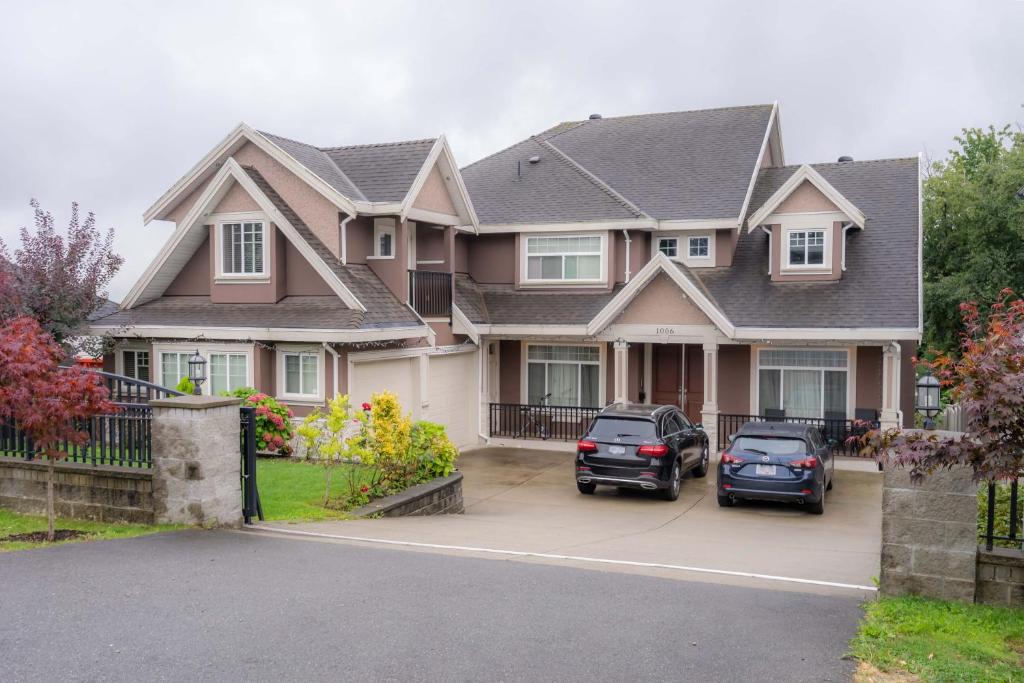 a house with two cars parked in a driveway at Vancouver Yuelai Guesthouse in Coquitlam