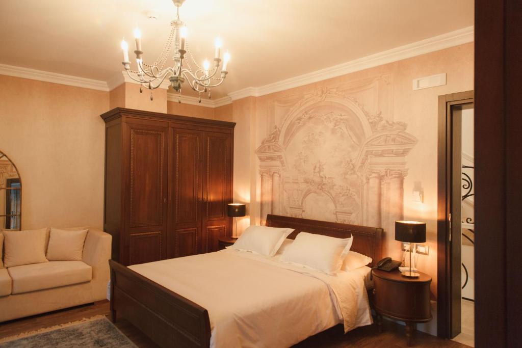 a bedroom with a bed and a chandelier and a chair at Hotel Boutique Vila 8 in Durrës