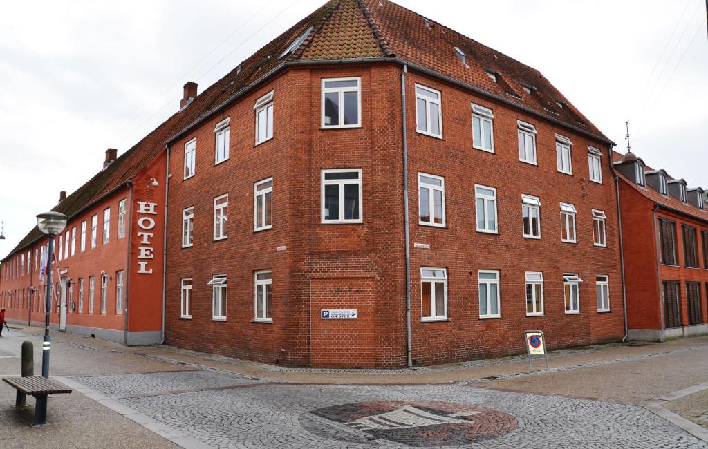 un grande edificio in mattoni rossi sul lato di una strada di Hotel Harmonien a Haderslev