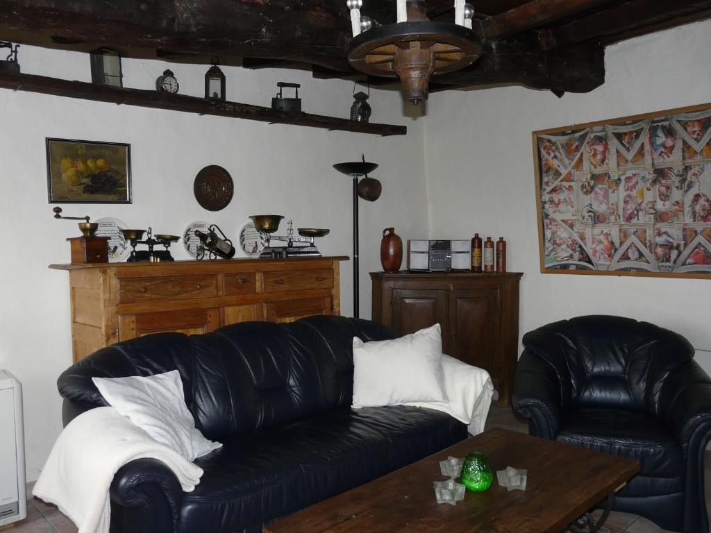 a living room with a black leather couch and a table at La Quitapenas in Ronse