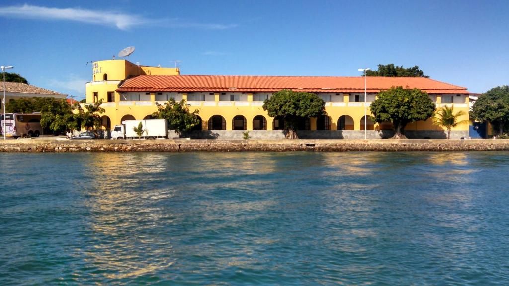un bâtiment jaune avec un toit rouge à côté de l'eau dans l'établissement Hotel Icaraí, à Itaparica Town