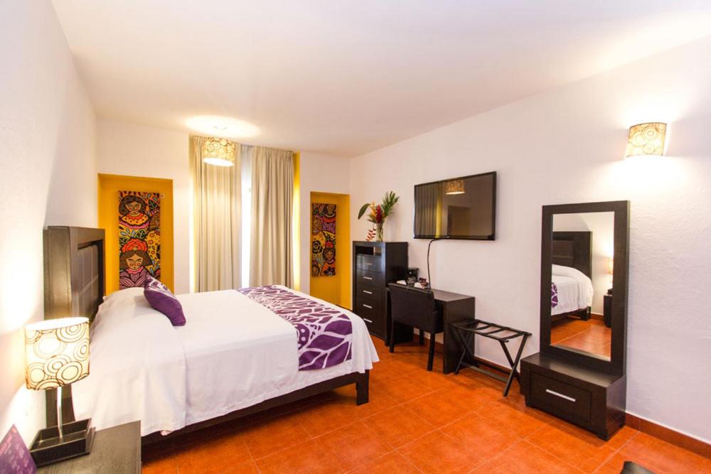 - une chambre avec un lit, un bureau et un miroir dans l'établissement Hotel Santa Cruz Huatulco, à Santa Cruz Huatulco
