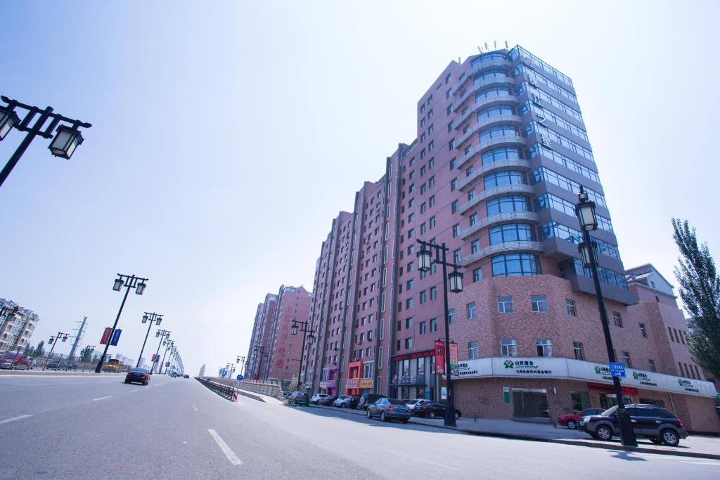 a tall building on a street with cars parked in front of it at Jinjiang Inn Datong Pingcheng Bridge in Datong
