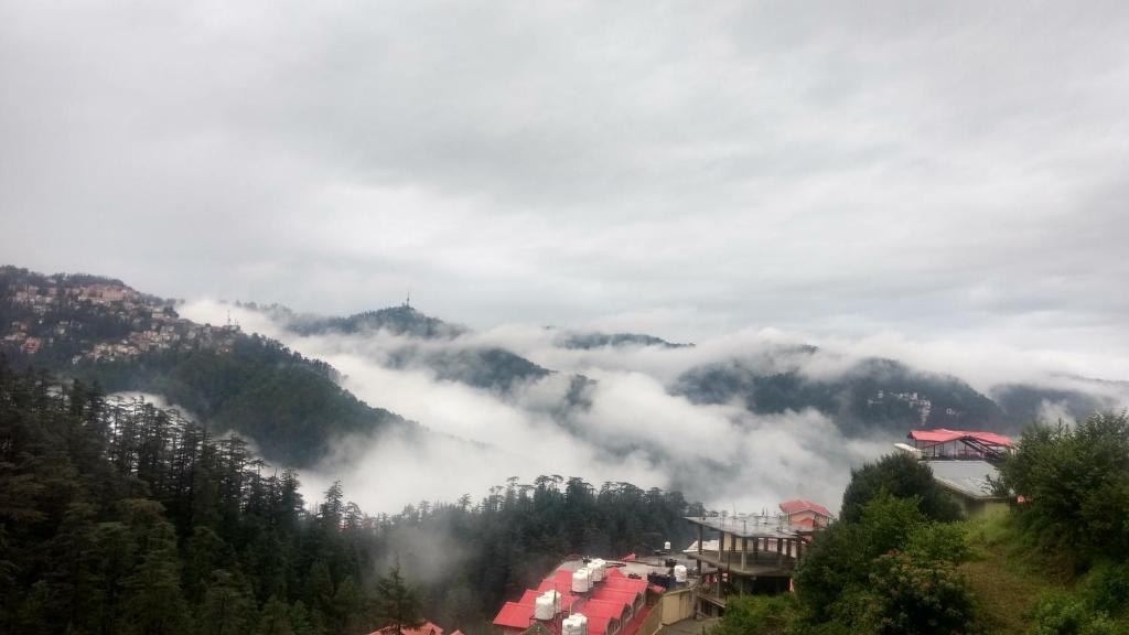 - une vue sur une montagne brumeuse avec des bâtiments et des arbres dans l'établissement Vipul Home Stay, à Shimla