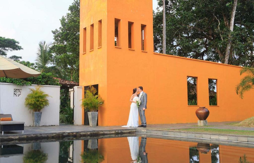 a bride and groom standing in front of a building at Kahanda Kanda in Koggala