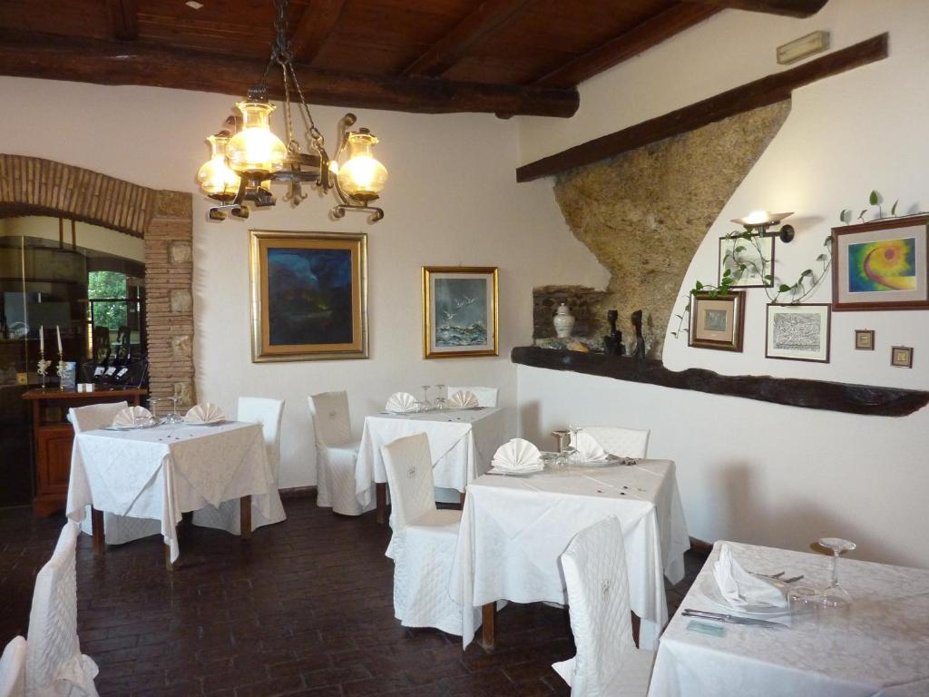 un comedor con mesas blancas y sillas blancas en La Rocca, en Narni