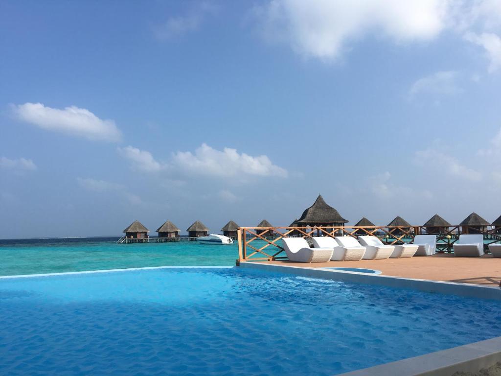 a resort swimming pool with chairs and the ocean at Thulhagiri Island Resort & Spa in North Male Atoll