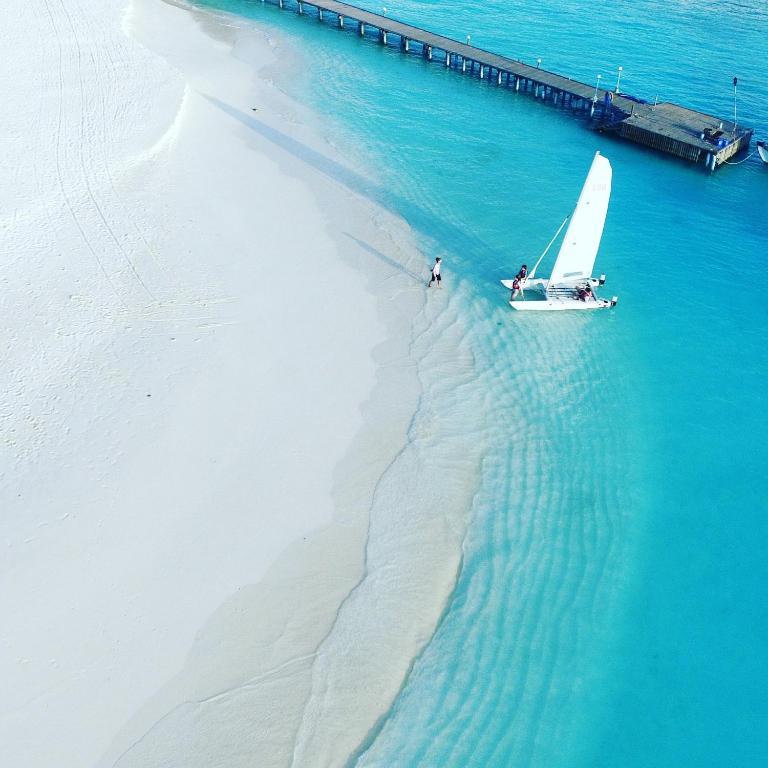 a small sail boat in the water next to a beach at Thulhagiri Island Resort & Spa in North Male Atoll