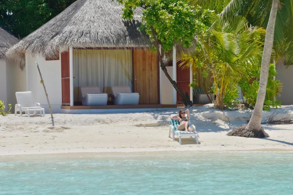two people sitting on a chair on a beach at Thulhagiri Island Resort & Spa in North Male Atoll