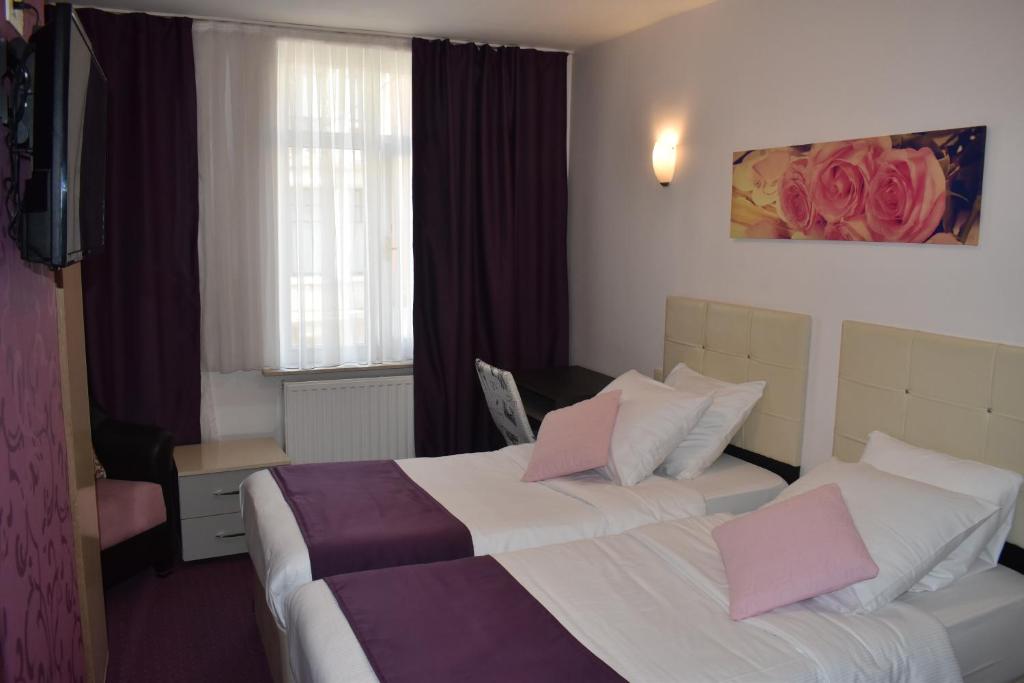 Habitación de hotel con 2 camas y almohadas rosas en Hôtel Méribel en Bruselas