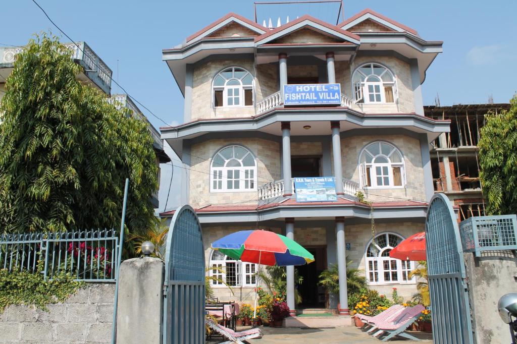 a building with an umbrella in front of it at Hotel Fishtail Villa in Pokhara