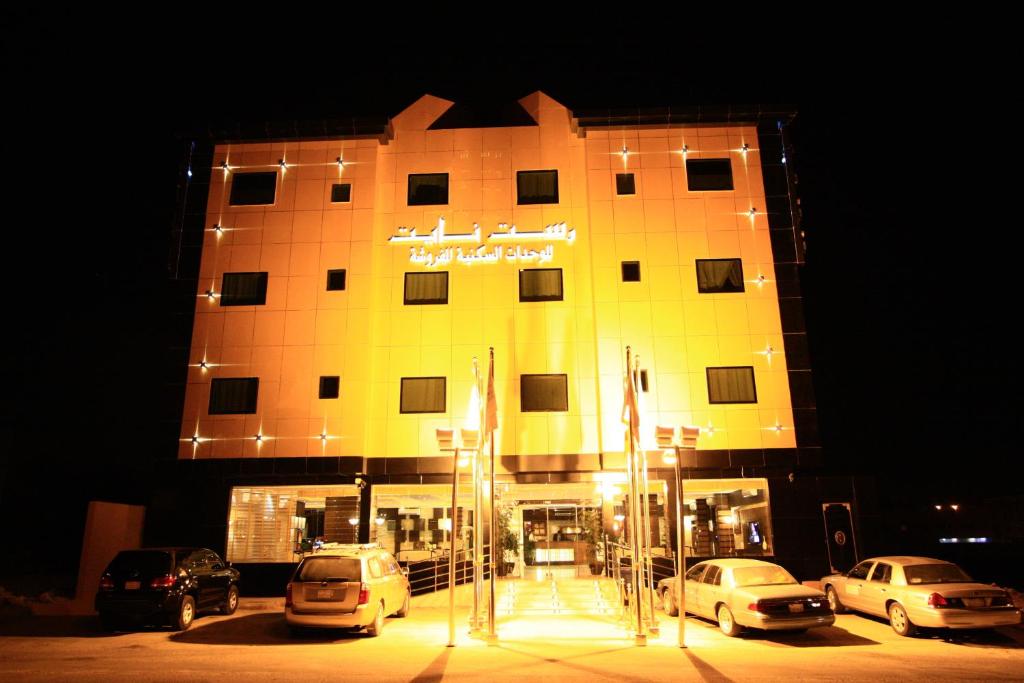 un gran edificio con coches estacionados frente a él en Rest Night Hotel Suites - Al Nafal, en Riad